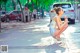 A woman sitting on the side of a street eating a piece of food.