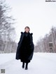 A woman in a black coat is walking in the snow.