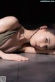 A woman laying on the ground with her head resting on her hands.