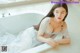 A woman in a white lingerie sitting in a bathtub.