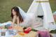 A woman in a wedding dress sitting on a picnic blanket.