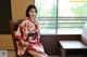 A woman in a red and white kimono sitting on a chair.