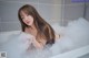 A woman taking a bath in a bathtub filled with foam.