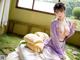 A woman in a purple kimono sitting on a bed.