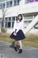 A woman in a school uniform standing in front of a building.