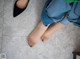 A woman's feet in black shoes on a tiled floor.